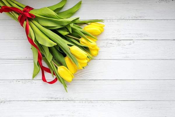 白い木製の背景に黄色のチューリップの花束。春を待っています。幸せな母の日カード、母の日、3 月 8 日。フラットの位置、平面図. — ストック写真