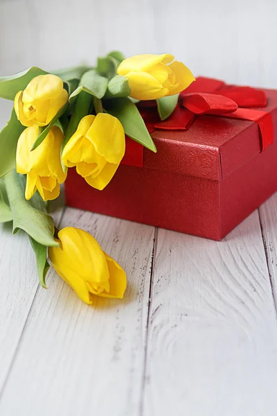 Yellow tulips flowers on white wooden background with gift. Waiting for spring. Happy holiday card. Flat position, top view. March 8. Place for text. — Stock Photo, Image