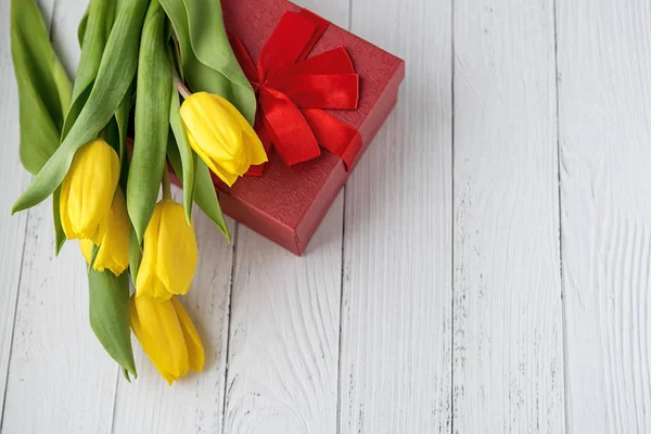 Flores de tulipas amarelas em fundo de madeira branco com presente. À espera da Primavera. Feliz cartão de Natal. Posição plana, vista superior. 8 de Março. Lugar para texto . — Fotografia de Stock