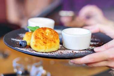 Süzme peynir yaban mersini ve nane ile kahvaltı ve öğle yemeği için krep. Kızın ellerini bitmiş çanak tutan.