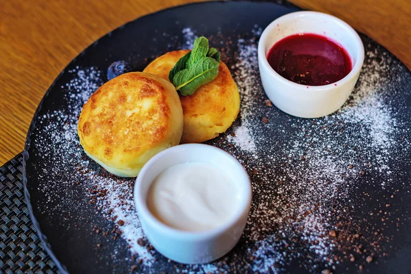 Panquecas de queijo cottage com mirtilo e hortelã para café da manhã ou almoço. Engarrafamento e nata azeda . — Fotografia de Stock