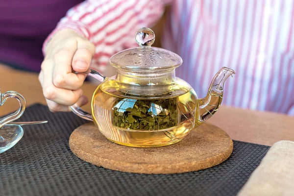 Teekanne mit Kräutertee vorhanden. das Konzept der gesunden Ernährung. Die Hand des Mannes hält eine Teekanne. — Stockfoto