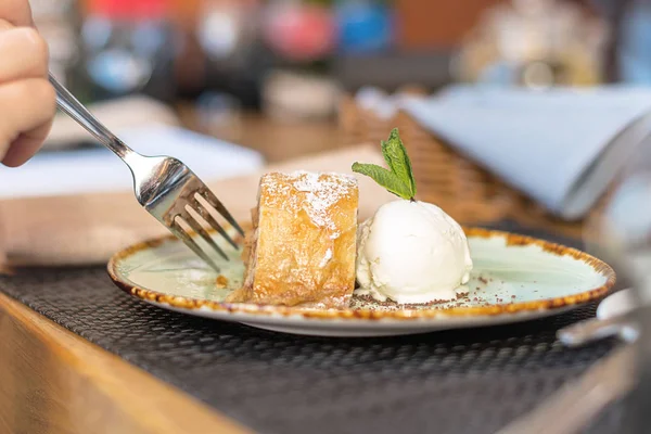 Apfelstrudel mit Vanilleeis und Minze. Hände werden mit Gabel geschnitten. — Stockfoto