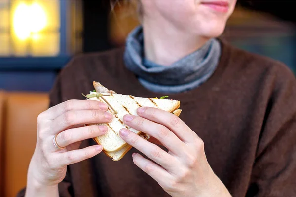 Mão de menina segurando uma deliciosa sanduíche de clube fresco. Fokus macio . — Fotografia de Stock