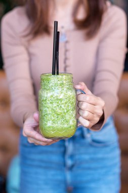 Smoothie shake onun önünde tutan kadın el. Bir sağlıklı yeşil smoothie kavram içme.