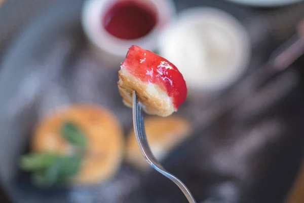 Deliciosa fatia de cheesecake com geléia em um garfo — Fotografia de Stock