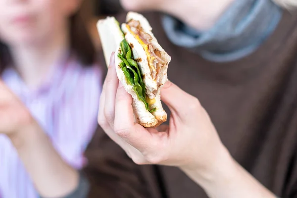 Mädchenhand hält ein leckeres Club-Sandwich. — Stockfoto