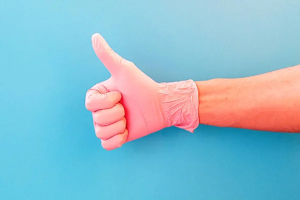 Thumbs up. Hand sign OK on blue background. Hand in pink gloves. — Stock Photo, Image