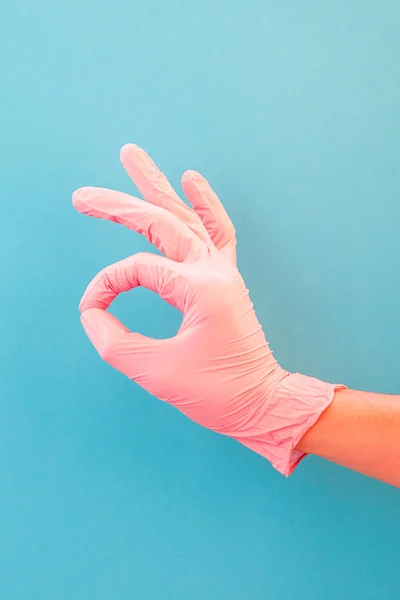 Signo de mano OK sobre fondo azul. Mano en guantes rosados . — Foto de Stock