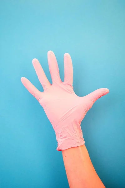 Apuntando con el dedo al número cinco, usando guantes médicos rosados, sobre un fondo azul. Buenos hábitos, vacunación, tienda médica, farmacia . — Foto de Stock