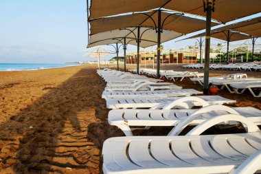 Güverte sandalyeleri sahilde sıralanmış, insanlar olmadan, sabahın erken saatlerinde, konsept gezi, tatil