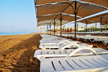 Güverte sandalyeleri sahilde sıralanmış, insanlar olmadan, sabahın erken saatlerinde, konsept gezi, tatil
