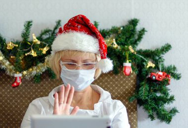 Noel çevrimiçi tebrikler. Gülümseyen kadın video için mobil tablet kullanıyor..