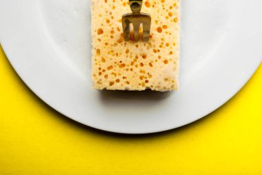 Sarı arka plan üzerinde beyaz bir plaka üzerinde temizlik süngeri