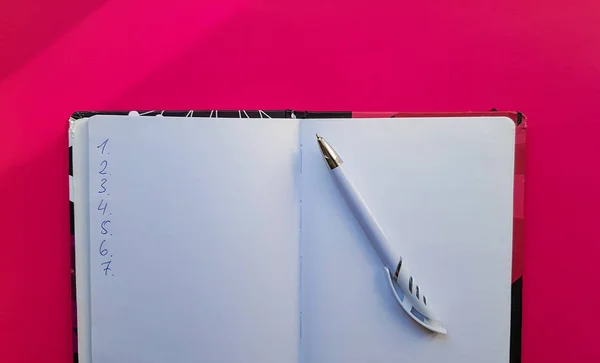 Carnet vierge avec stylo blanc sur fond rouge. Pages vides d'un livre ouvert, espace pour l'écriture et le texte. Vue d'en haut. Espace de copie, pose plate — Photo