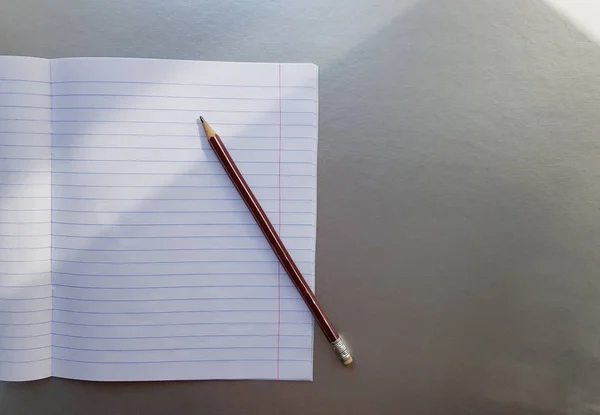 Carnet scolaire ouvert avec stylo sur un bureau gris avec des rayons de soleil de la fenêtre. Une feuille blanche vierge de cahier pour écrire. concept d'éducation. Espace de copie. vue d'en haut. Pose plate — Photo