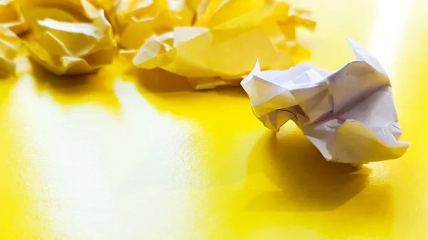 Ball crumpled paper ball isolated on a yellow background. Crumpled paper for texture. Crumpled paper after a brainstorming was thrown into the bin. A piece of yellow crumpled paper on a yellow backgro