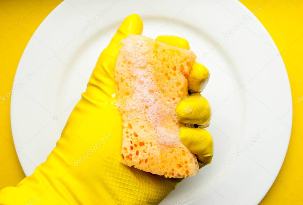 Cleaning sponge on a white plate on a yellow background