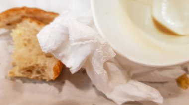 Bir fast food kafede ahşap bir masada bir kağıt tabak ve boş kirli kağıt kahve fincanı üzerinde artık gıda