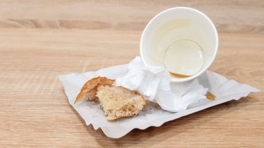 Bir fast food kafede ahşap bir masada bir kağıt tabak ve boş kirli kağıt kahve fincanı üzerinde artık gıda
