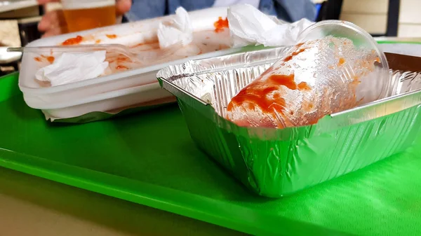 Megmaradt élelmiszer, piszkos műanyag edények egy zöld tálcát egy asztalon egy szabadtéri kávézóban — Stock Fotó