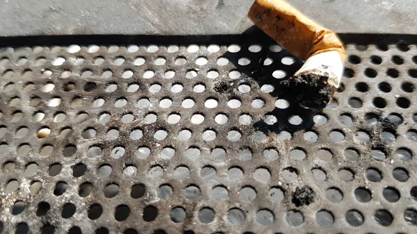 Ein Zigarettenstummel auf einem öffentlichen Aschenbecher mit Metallhintergrund — Stockfoto