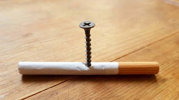 Screw and yellow background. Screw screwed into a cigarette. Anti-smoking concept — Stock Photo, Image