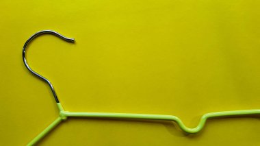 Sarı arka plandaki kıyafetler için askı. Yeşil askı. Kopyalama alanı ile arka plan. Kara Cuma, alışveriş günü