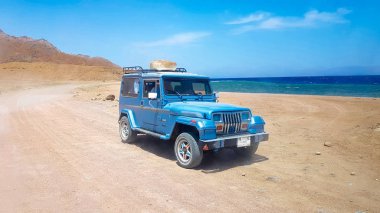 Mısır, Şarm El Şeyh - 07 Haziran 2019: Mavi Jeep Suv deniz kıyısı boyunca kumlu bir yolda sürmek