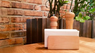 Kafe veya restoranda bir masa. Ahşap peçete likte beyaz peçeteler, ahşap bir masada baharat tuz ve karabiber, panoramik manzara