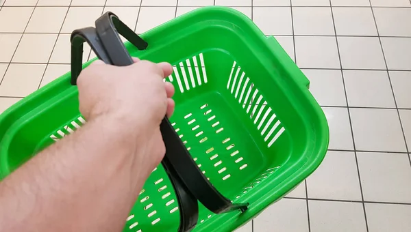 Hand neemt een groene lege winkelmand in een markt of supermarkt — Stockfoto