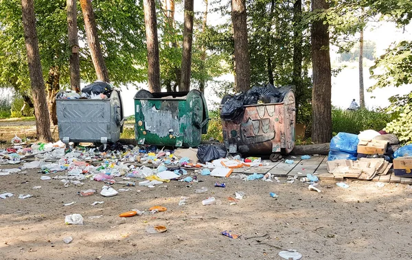 Ukraina, Kijów-11 września 2019: stare zardzewiałe pojemniki na śmieci pełne z odpadów plastikowych i rozproszonych śmieci, stojąc w parku miejskim lub lesie. Zanieczyszczenie środowiska — Zdjęcie stockowe