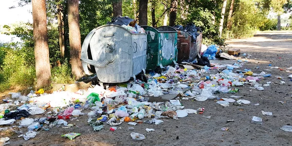 Ucrania, Kiev - 11 de septiembre de 2019: Viejos contenedores de basura metálica oxidada llenos de residuos plásticos y basura dispersa, de pie en un parque o bosque de la ciudad. Contaminación ambiental — Foto de Stock