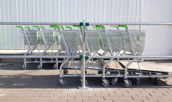 Um carrinho de compras em um shopping, usado como imagem de fundo. Uma fileira de carrinhos de mão para fazer compras em um supermercado de construção ao ar livre — Fotografia de Stock