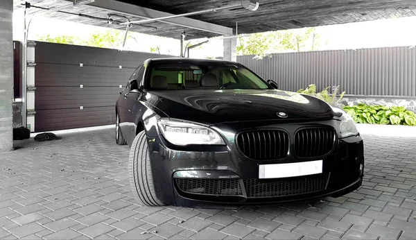 Ukraine, Kiev - 12 septembre 2019 : Une nouvelle berline BMW VIP de luxe en noir et gris est garée devant la porte de garage de la maison — Photo