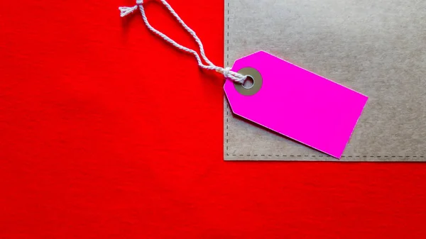 Étiquette vierge en carton violet, étiquette de prix sur papier artisanal sur fond de tissu rouge. Espace de copie, place pour le texte, pose plate — Photo