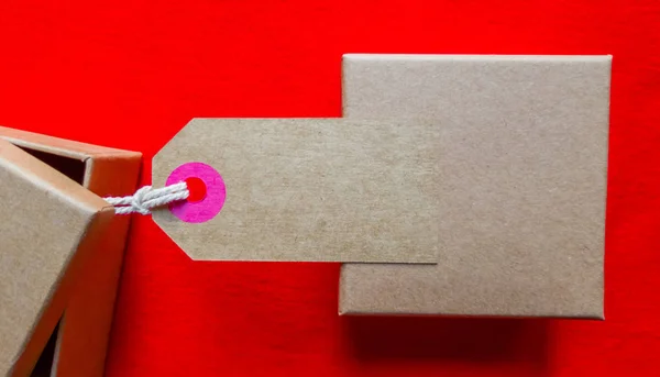 Boîtes en carton avec une étiquette. Boîte d'emballage marron avec étiquette vierge et espace de copie sur fond rouge — Photo
