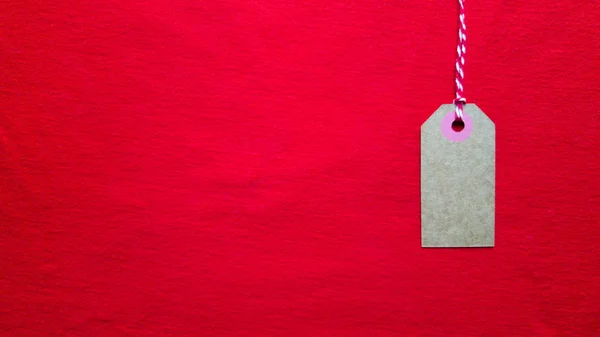 Étiquette rouge accrochée à une corde rouge sur un fond rouge. Espace de copie, place pour le texte, pose plate . — Photo