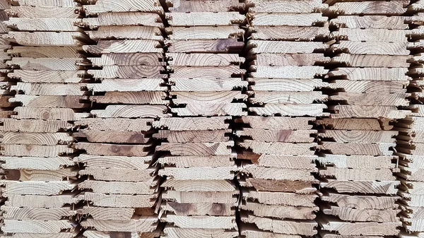 A pile of new wooden boards in stock. Production line of a factory of wooden floors. Industrial background