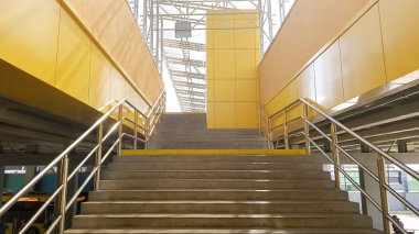 hafif raylı sistem istasyonu. Sarı paneller ve cam çatıdan yapılmış basamak ve korkuluklar ile bir otobüs durağı ve bir yaya alt geçit tasarımı.