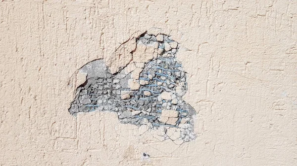 Ammaccatura su un muro di cemento giallo. Foro nel muro con isolamento in schiuma. Crack sulla parete gialla con stucco decorativo — Foto Stock