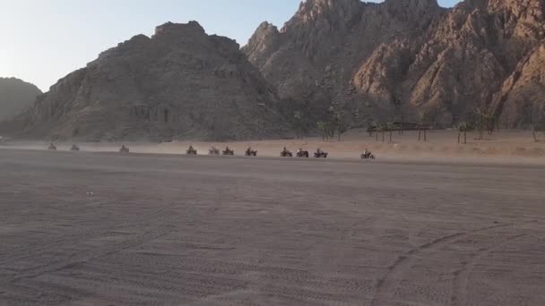 Egipto, Sharm El Sheikh - 20 de junio de 2019: un grupo de turistas en vehículos todo terreno recorre el desierto con el telón de fondo de las montañas. Conducción en ATV. El grupo se estableció en los vehículos todo terreno, los egipcios ofrecen — Vídeos de Stock