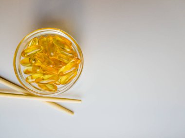 Çubuklu bir tabakta balık yağı kapsülleri. Balık yağı kapsülleri. Beyaz arka planda Omega 3 balık yağı kapsülleri. Beyaz arka plan üzerinde kapsül Omega 3 yığını. Yakın çekim, üst görünüm, yüksek çözünürlük