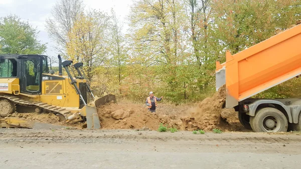 Ukraina, Kijów - 1 października 2019: Wałek drogowy, ciągnik i sprzęt budowlany pracują na nowym placu budowy dróg. Droga jest zamknięta dla naprawy dróg, przedłużenia trasy, naprawy otworów pothole — Zdjęcie stockowe