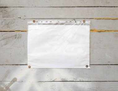White paper sign with rivets, vintage background on a gray wooden old backdrop. Wooden textured wall, weighs a white blank cardboard sign lit by the sun, closeup clipart