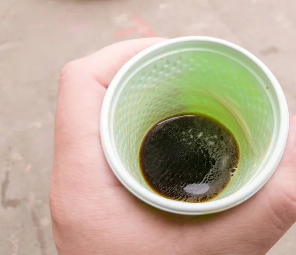 Taza de plástico verde con café negro en la mano de un hombre al aire libre. Un hombre tiene un vaso de café en la mano. Vista desde arriba . —  Fotos de Stock