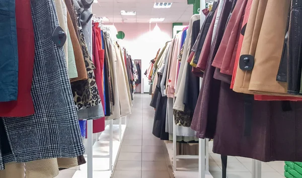 Roupas penduradas em prateleiras em uma loja de roupas de grife. Loja de Roupas. corredor de roupas em um supermercado . — Fotografia de Stock