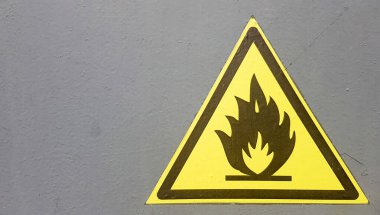 Yangın uyarı simgesi, gri arkaplandaki sarı etiketi imzalayın. Yanıcı madde. Metal duvardaki sarı üçgen. Kopyalama alanı olan arkaplan.