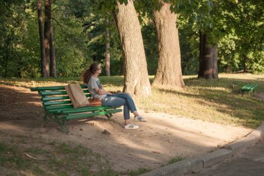 Ukrayna, Kiev - 6 Temmuz 2019. Parktaki bankta tek başına oturan genç kız. Güneşli bir yaz gününde sevgili bekleyen güzel bir kadın..