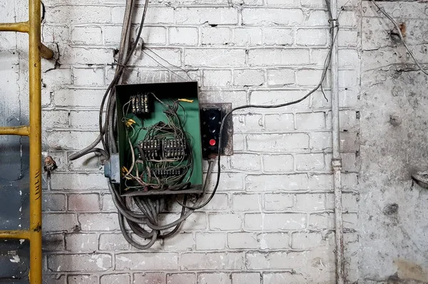 Velho painel eléctrico na parede da casa. Cabos elétricos se destacam do painel elétrico na parede de tijolo branco da casa velha . — Fotografia de Stock